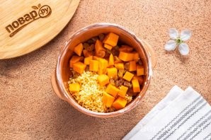 Шаг 10: Выложите в горшочек для запекания пшенную крупу, тыкву и изюм. Края горшочка смажьте сливочным маслом, чтобы после было проще убирать пленку от молока.