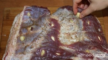 Шаг 1: Свинину тщательно промойте. Нашпигуйте её чесноком. Смешайте соль, перец и приправу по вкусу, тщательно смажьте этой смесью мясо со всех сторон.